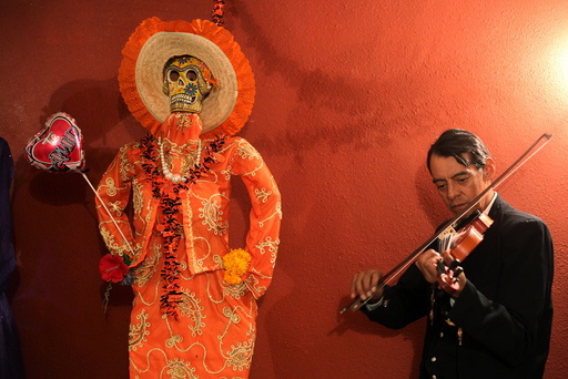 Musician plays his violin next to a depiction of La Santa Muerte (Saint Death) at a shrine during Day of the Dead celebrations in Ciudad Juarez