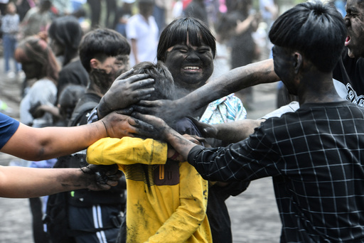 People smear black ash with hands onto each other during Monihei Carnival in Puer