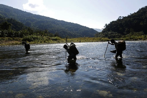 Naga men walk though a creek during a hunting trip between Donhe and Lahe township in the Naga Self-Administered Zone