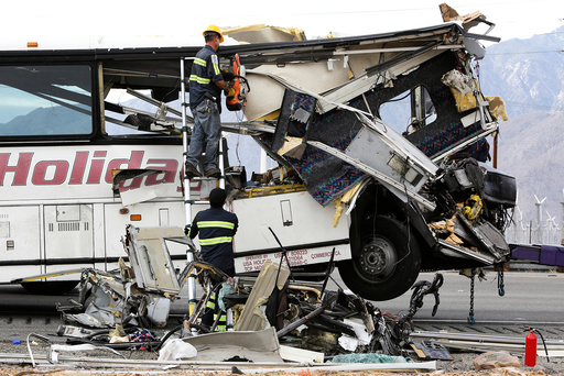 Workers cut away debris from the front of a bus involved in a mass casualty crash on the westbound Interstate 10 freeway near Palm Springs, California