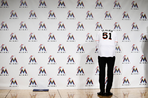 Japan's outfielder Suzuki, wearing his new Marlins hat and jersey, poses for pictures as he is asked to show his number during news conference to announce an agreement on a one-year contract with the Miami Marlins, in Tokyo