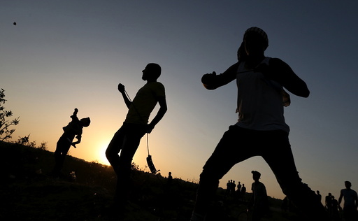 Palestinian protesters hurl stones at Israeli troops during clashes near the border between Israel and Central Gaza Strip