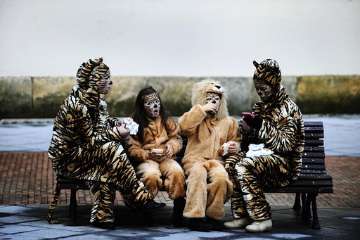 Two mothers and their children eat before participating in the parade of the Carnival in Gijon