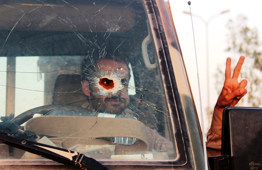 Yemeni soldier, pictured through a vehicle's windscreen, which was damaged by a bullet, gestures out of the window, in Marib, Yemen