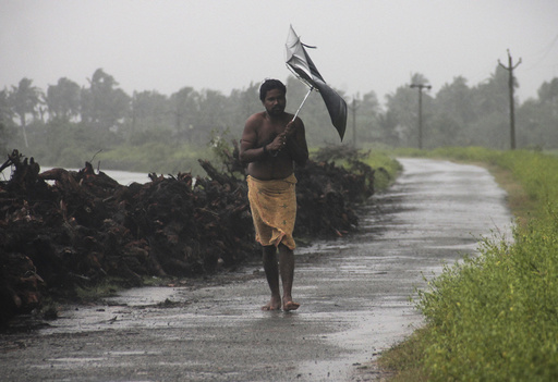 A man struggles with an umbrella in strong winds and rain caused by Cyclone Hudhud in Gopalpur in Ganjam district