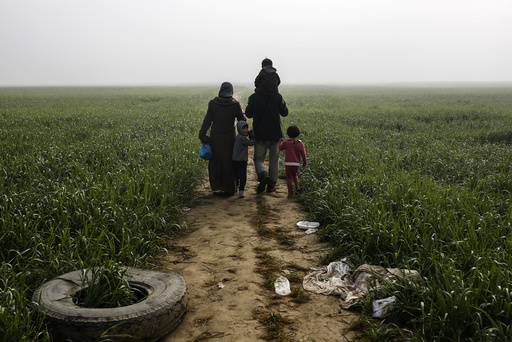 A family walks through a field at a makeshift camp for migrants and refugees at the Greek-Macedonian border near the village of Idomeni