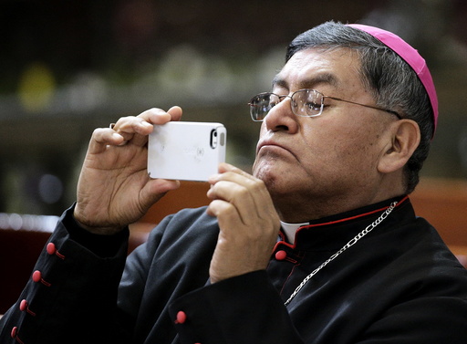 A bishop uses a mobile phone during a meeting with Pope Francis at the Metropolitan Cathedral in Zocalo Square in Mexico City
