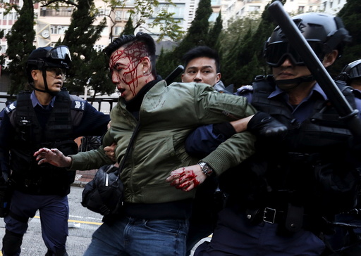 An unidentified injured man is escorted by riot police at Mongkok in Hong Kong