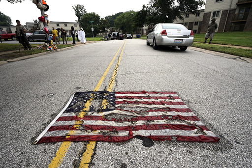 Partially burned American flag lies on the street near the spot where Michael Brown was killed before an event to mark the one-year anniversary of the his death in Ferguson