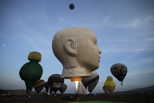 Hot air balloons are prepared for a flight as others take off during an international hot air balloon festival at Maayan Harod National park in northern Israel