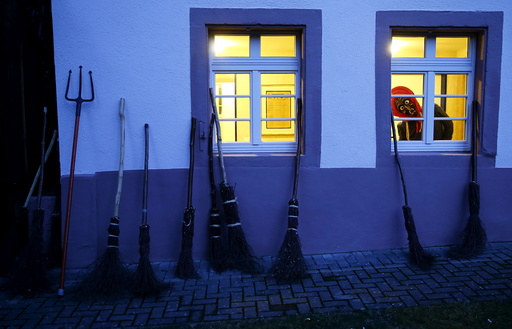 A carnival reveller dressed as a witch (Kandelhexe) looks out of a window as a group of traditional witches meet prior to their traditional witches sabbath performance in the Black Forest village of Waldkirch