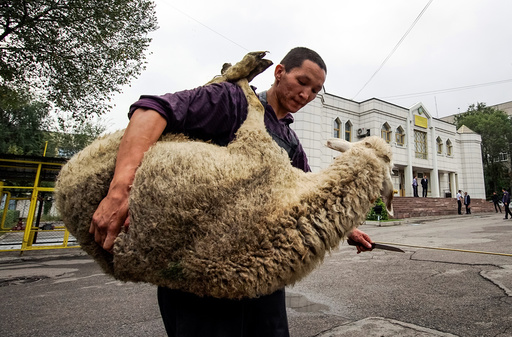 A butcher carries a sheep for slaughtering to mark Kurban-Ait, also known as Eid al-Adha, in the Central Mosque in Almaty, Kazakhstan