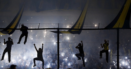 Boca Juniors' fans climb onto the tribune fence as they cheer their team on before their Copa Libertadores soccer match against River Plate in Buenos Aires
