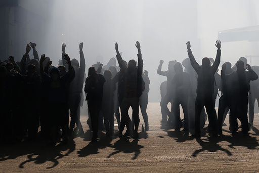 Tear gas fills the air as masked and hooded demonstrators put their hands in the air as they are surrounded by French police and gendarmes at the end of a demonstration against the French labour law proposal in Nantes