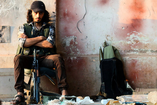 A rebel fighter sits with his weapon in the artillery academy of Aleppo