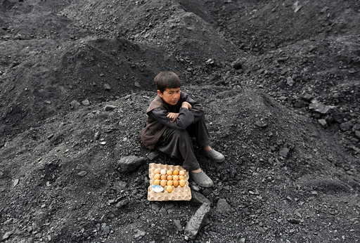 An Afghan boy selling boiled eggs waits for customers at a coal dump site on the outskirts of Kabul