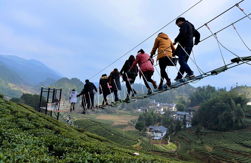 Tourists walk above a tea plantation in Enshi