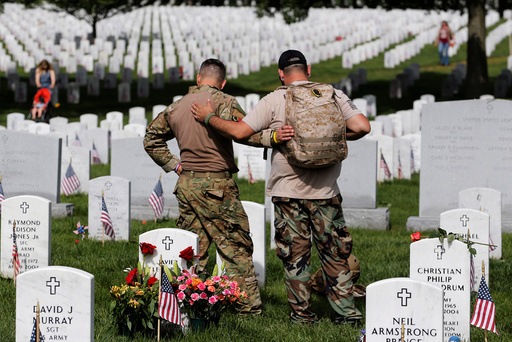 U.S. Army soldiers Rick Kolberg and Jesus Gallegos embrace as they visit the graves of Raymond Jones and Peter Enos on Memorial Day at Arlington National Cemetery in Washington