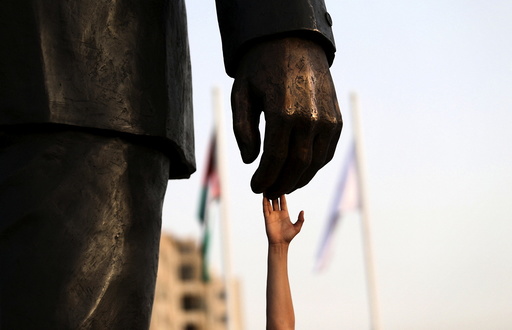 A Palestinian man touches the Mandela statue during the inauguration of Nelson Mandela Square in the West Bank city of Ramallah