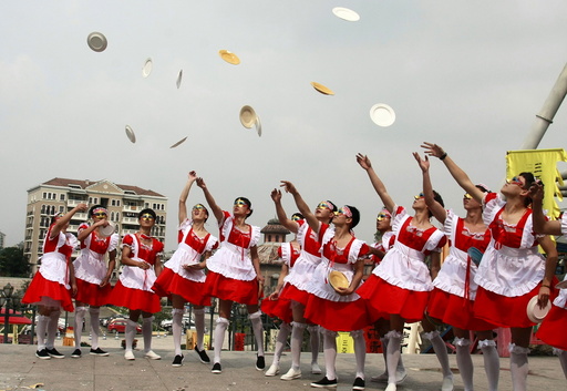 Male staff members of an amusement park wearing maid costumes throw chinaware into the air to be smashed during an event promoting their stress-release activities to mark World Mental Health Day, in Hangzhou