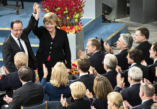 German Chancellor Merkel and French President Hollande hold up hands during the Nobel Peace Prize ceremony at the City Hall in Oslo