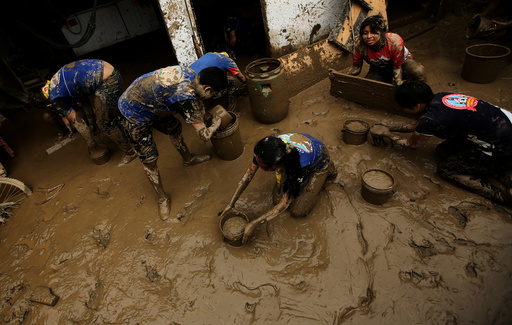 Volunteers clean a flooded home after rivers breached their banks due to torrential rains causing flooding and widespread destruction in Cajamarquilla, Lima
