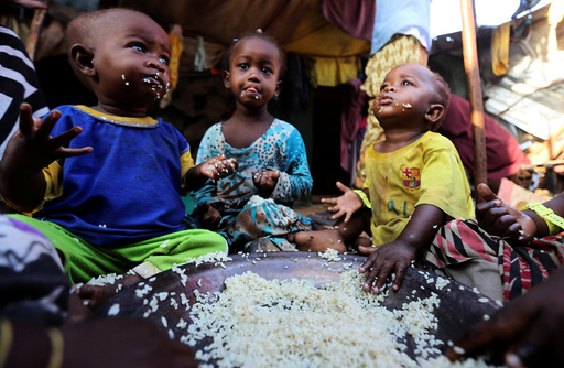 Internally displaced Somali children eat boiled rice outside their family's makeshift shelter at the Al-cadaala camp in Somalia's capital Mogadishu
