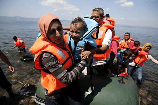 A Syrian refugee carries her baby as she arrives with other Syrian refugees on a dinghy on the island of Lesbos