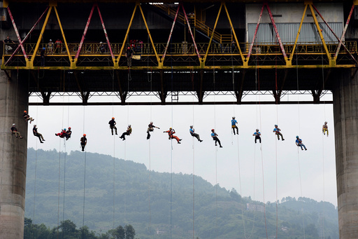 People slide down a rope from a bridge during a rescue training in Chongqing