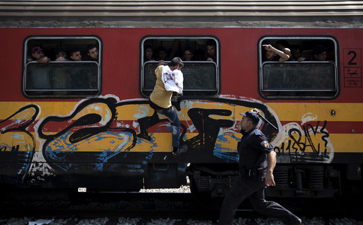 Policeman tries to stop a migrant from boarding a train through a window at Gevgelija train station in Macedonia, close to the border with Greece