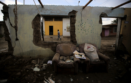 A man walks next to a flooded home damaged after heavy rain in Castilla district of Piura