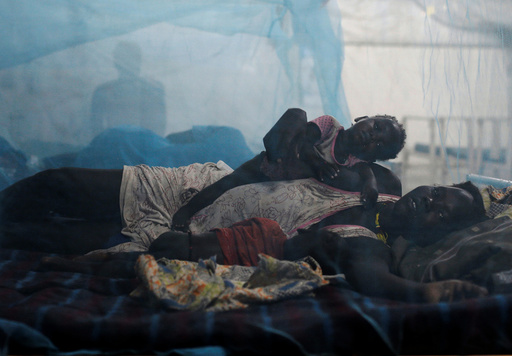 A woman rests in bed with her children in the paediatric ward at the Medecins Sans Frontieres (MSF) hospital inside the UNMISS base in Bentiu, Rubkona County