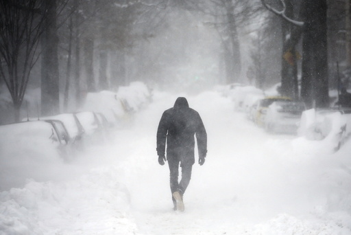 A man walks along a street covered by snow during a winter storm in Washington