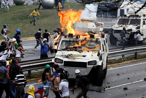 Demonstrators clash with a riot police armored car in Caracas