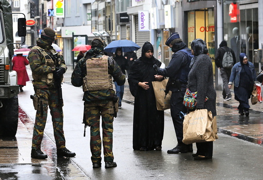 Belgian soldiers and a police officer control documents of a woman in a shopping street in central Brussels after security was tightened in Belgium following the fatal attacks in Paris