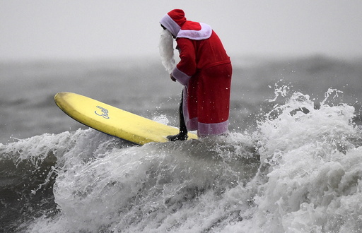 A member of the Langland Board Surfers group takes part in a Surfing Santa competition at Langland Bay in Gower