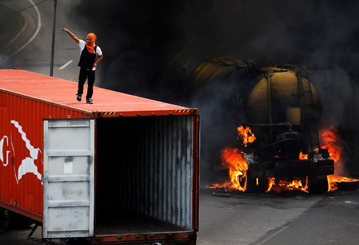 Demonstrator stands on top of a truck set on fire to build a barricade while rallying against Venezuela's President Nicolas Maduro's Government in Caracas