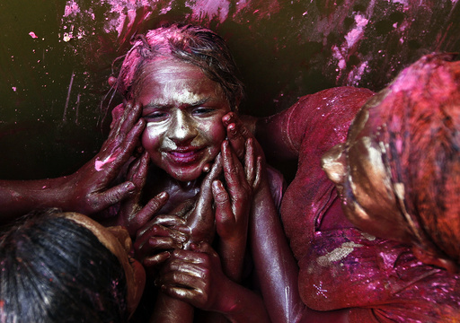 A girl reacts as other girls apply coloured paint on her face during Holi celebrations in Chennai