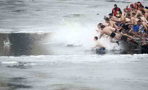 Men jump into the waters of a lake in an attempt to grab a wooden cross on Epiphany Day in Sofia