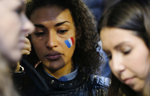 A woman wears the painted colours of France's national flag on her cheek during a candlelight vigil for the victims of the Paris attacks, in Sydney, Australia
