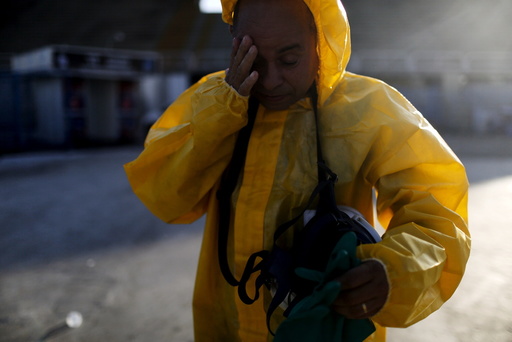 Municipal worker touches his face as he finishes spraying insecticide at Sambodrome in Rio de Janeiro