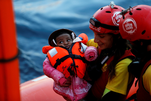 A crew member of MV Open Arms carries a migrant baby before passing it to crew members of MV Aquarius during a mid-sea transfer of migrants in the central Mediterranean off the coast of Libya