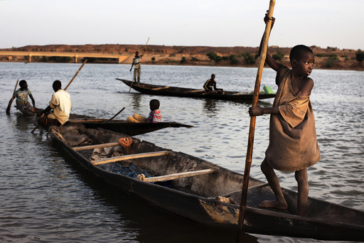 Men and boys fish in canoes in the Niger River in Gao