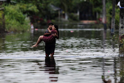 A man carries his wife on a flooded street after heavy rainfall in Milagro