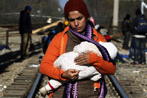 A stranded migrant holds a baby as she waits next to the Greek-Macedonian border near to the Greek village of Idomeni