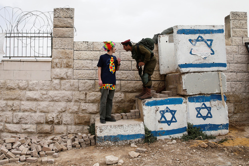 A man dressed in costume chats with an Israeli soldier as he takes part in a parade marking the Jewish holiday of Purim in the West Bank city of Hebron