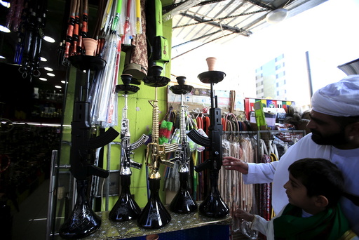 People inspect hookahs shaped like rifles on display for sale in a souk at the port city of Sidon