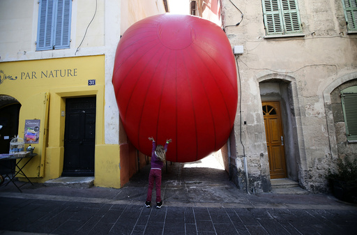 A child plays with a huge red ball which is installed between two buildings as part of the RedBall Project by artist Kurt Perschke in Marseille