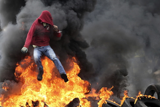 Palestinian protester jumps over burning tyres during clashes with Israeli troops near the Jewish settlement of Bet El, near the West Bank city of Ramallah
