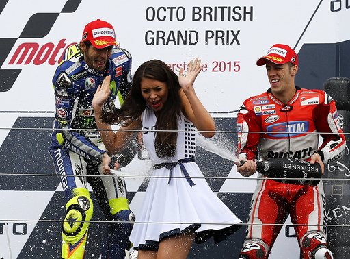 Winning Yamaha MotoGP rider Valentino Rossi of Italy and third placed Ducati MotoGP rider Andrea Dovizioso of Italy spray a grid girl after the British Grand Prix at the Silverstone Race Circuit